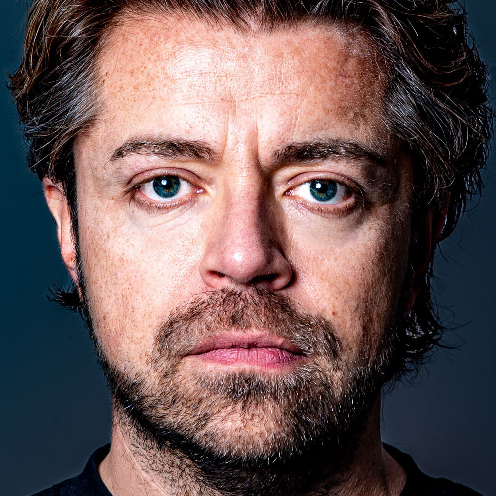 Daan van der Hoeven kijkt recht de camera in met serieuze blik en lichte baardgroei.