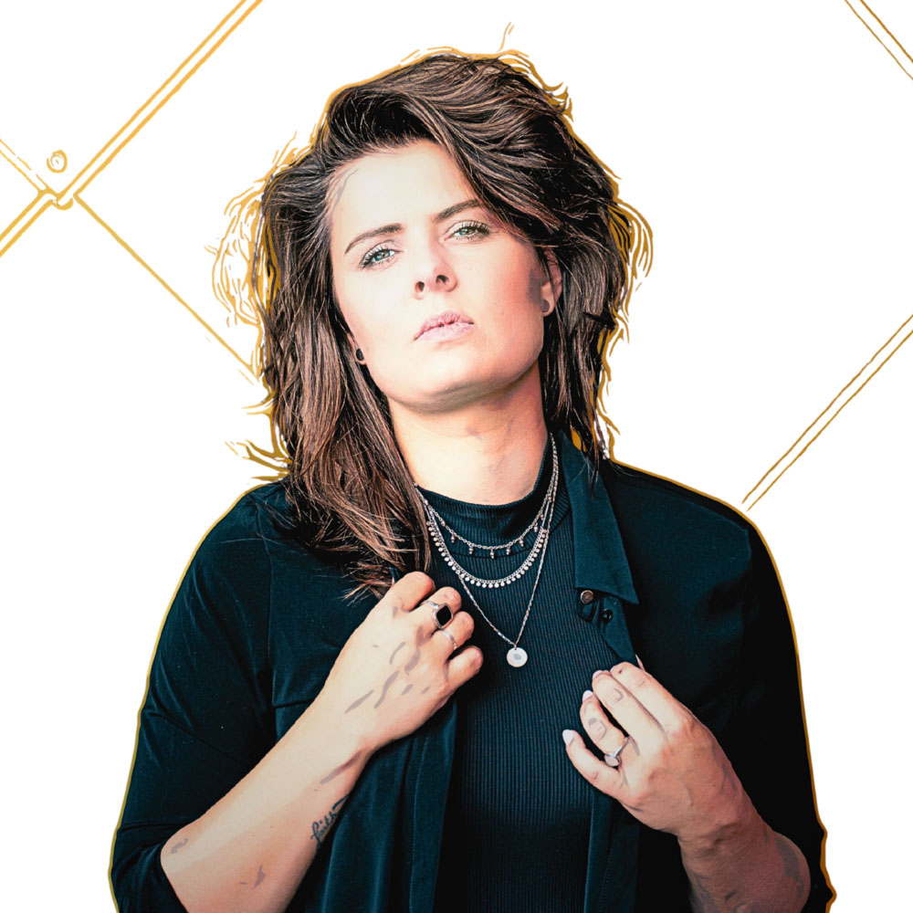 Mell VF kijkt recht in de camera met een serieuze blik en houdt haar jas vast.