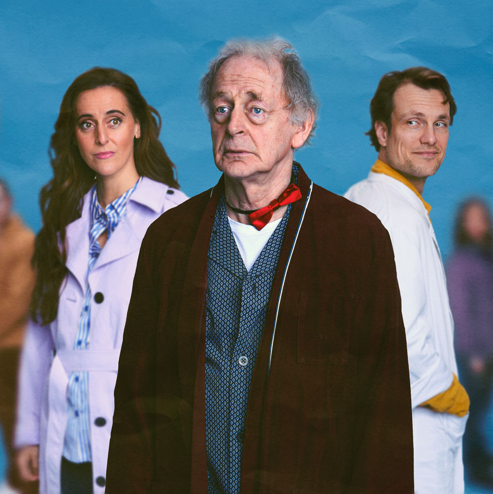 Oudere man in kamerjas kijkt ernstig, met een vrouw en arts op de achtergrond.