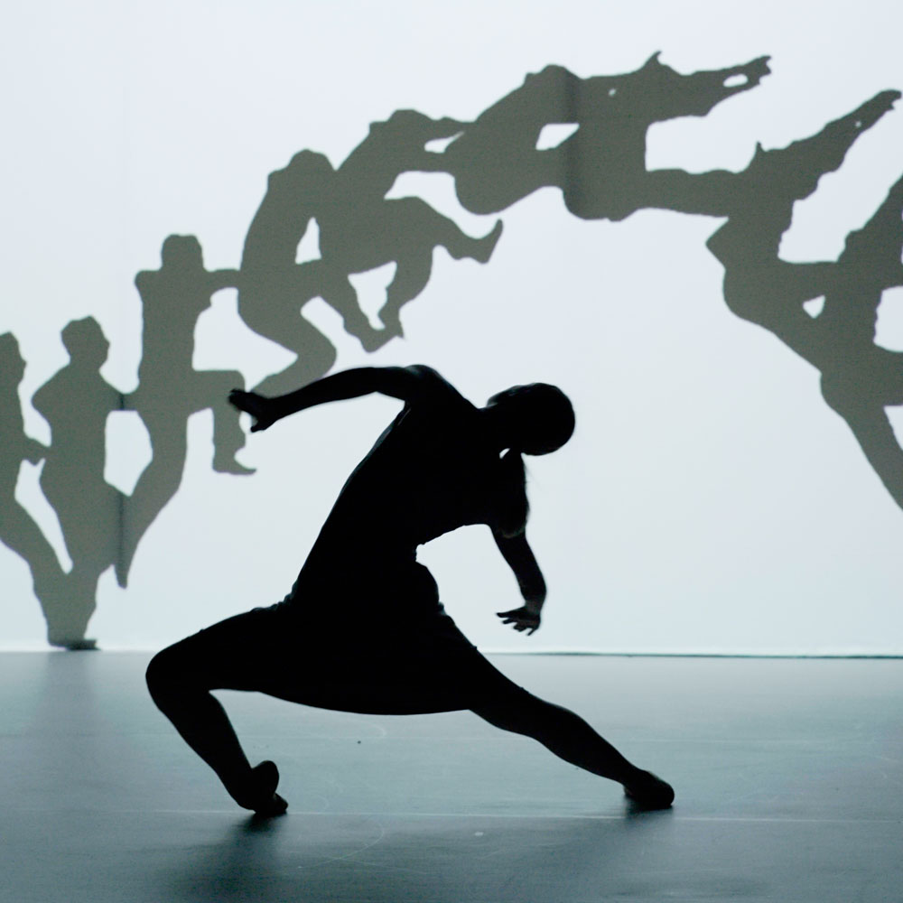 Danser in silhouet beweegt krachtig voor projectie van springende figuren.