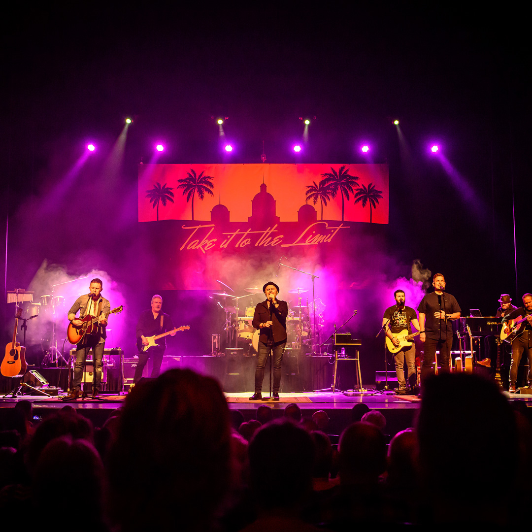 Tribute band brengt ode aan The Eagles met liveoptreden op sfeervol verlicht podium.