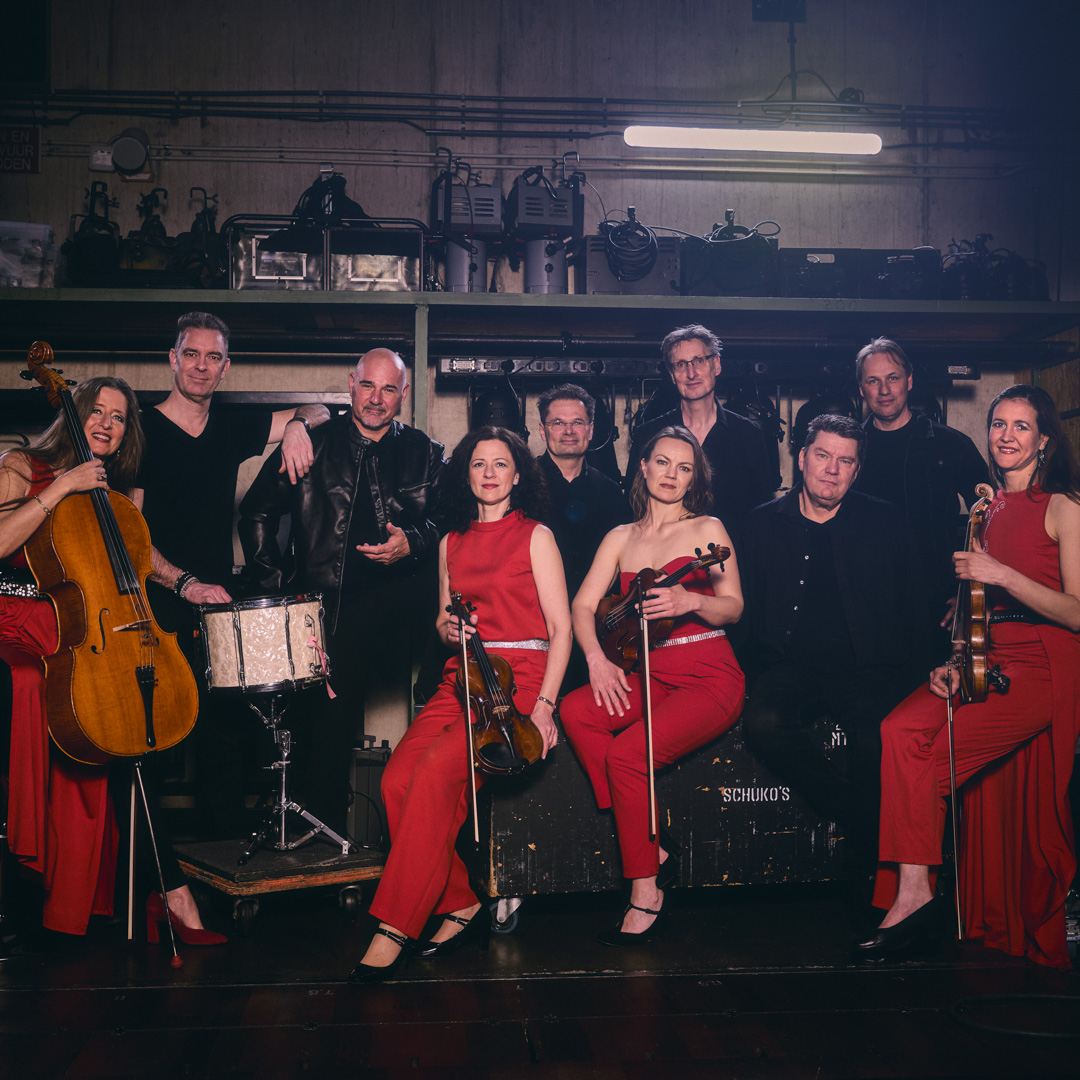 The Billy Joel Experience muzikanten, twee vrouwen met viool in rode outfit op de voorgrond.