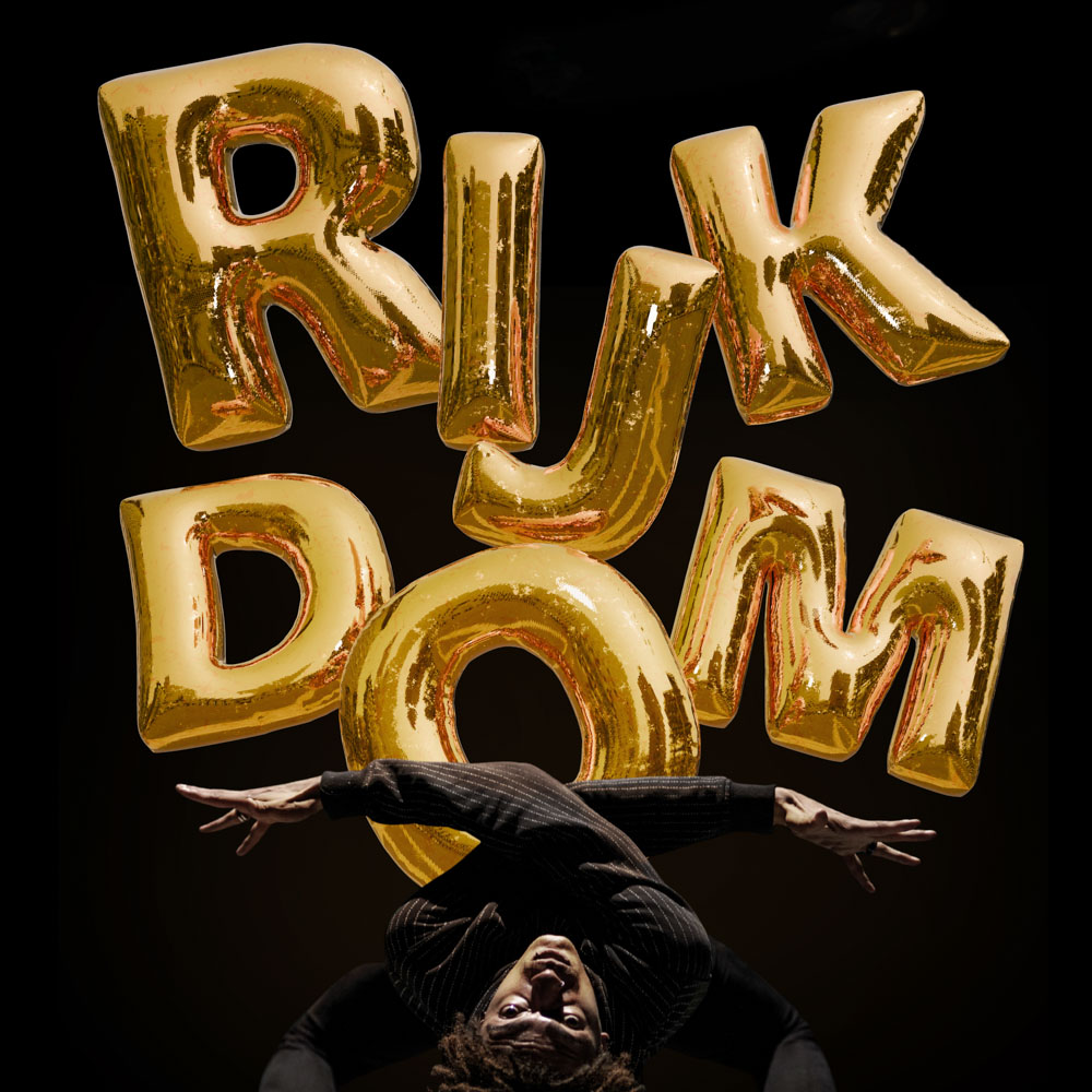 Danser van Xclusiv Company hangt ondersteboven voor gouden ballonletters Rijk Dom.